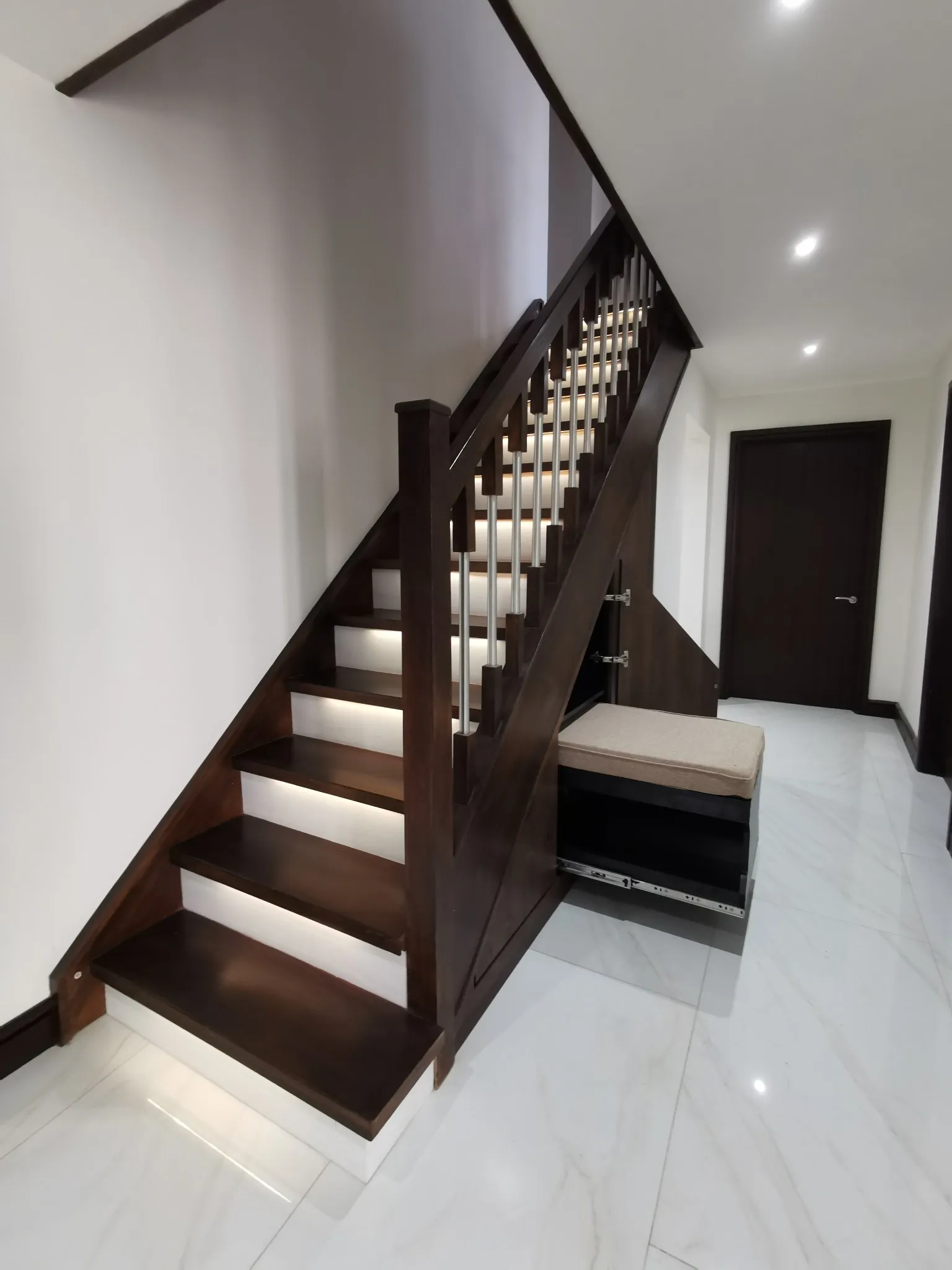 A dark walnut under stairs run with the bench seat open