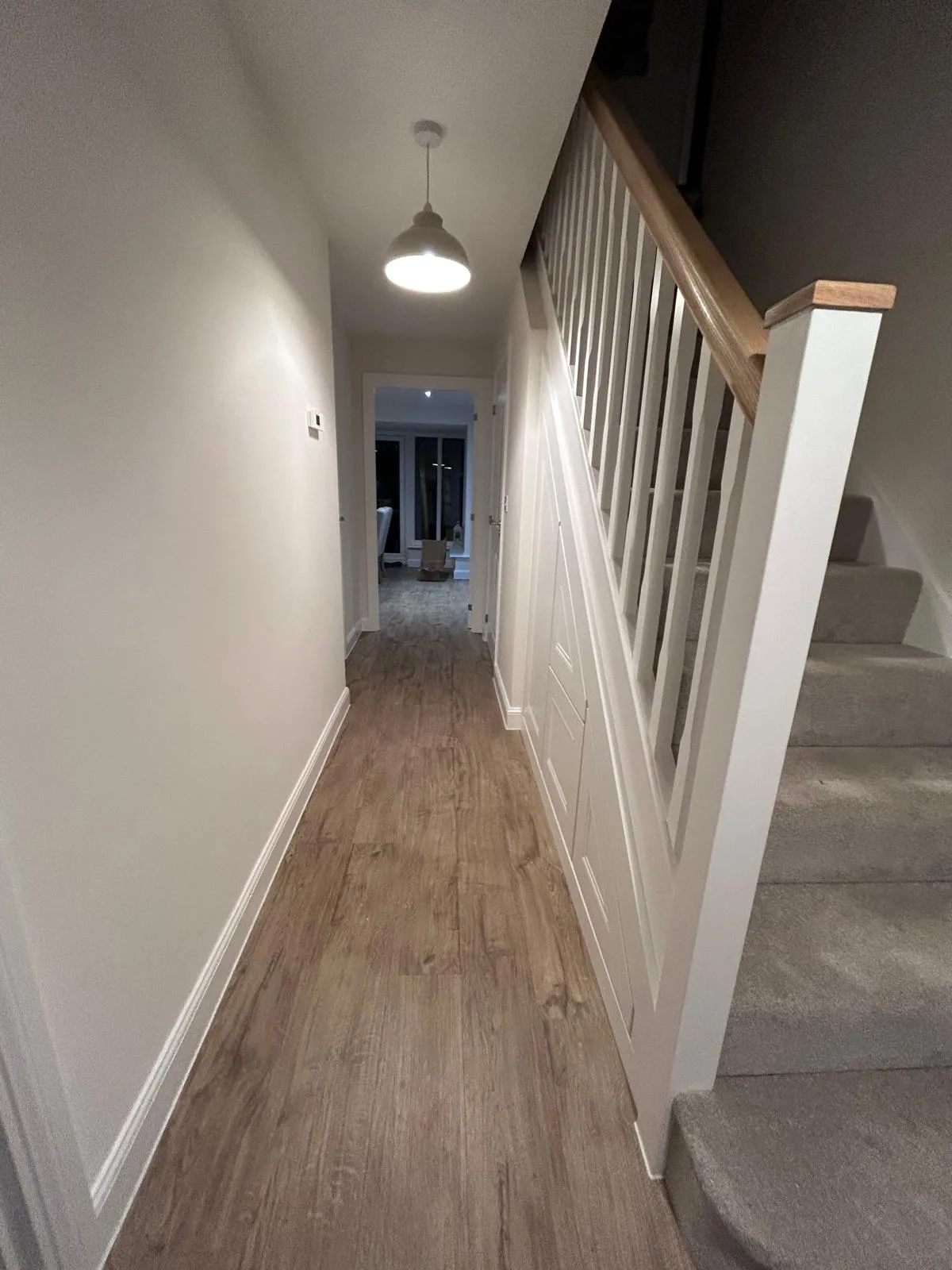 A hallway with a panelled under stairs storage run fitted flush beside the staircase