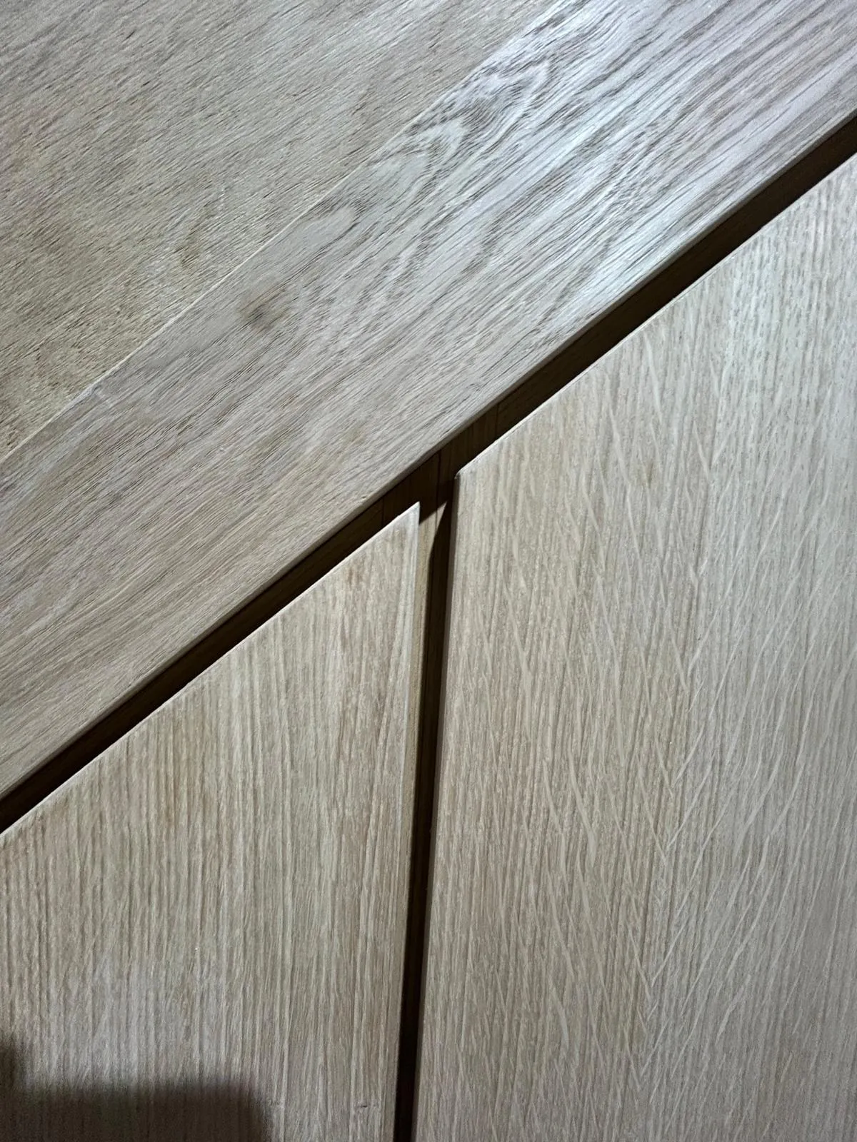 Close up of the signature 10mm shadow gap between oak woodgrain doors beneath the stair stringer